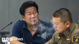 Former lawmaker Chalong Riewrang smokes at a police station where he held a press conference.