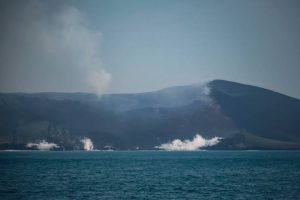 Mount Anak Krakatau billows smoke from its crater and lava flows send up clouds of steam as they reach the sea, as seen from the waters of the Sunda Strait on Sept. 12.